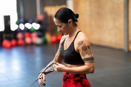 Starke reife Frau schützt ihre Handgelenke vor dem Training im Fitnessstudio mit Wickeln