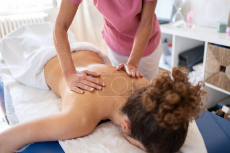 Photo for High angle of crop anonymous masseuse kneading back of woman during treatment in physical therapy clinic releasing muscle tension - Royalty Free Image