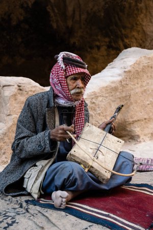 Foto de Siq el-Barid, Jordania - 29 de octubre de 2022: Hombre beduino jordano mayor tocando el violín Rababah de una cuerda - Imagen libre de derechos