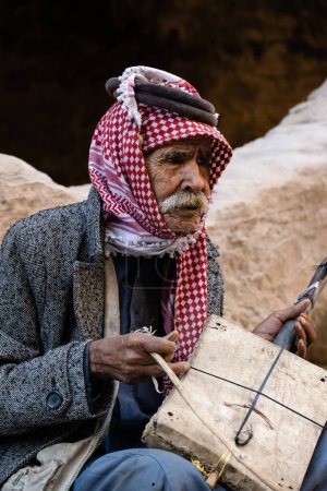 Foto de Siq el-Barid, Jordania - 29 de octubre de 2022: Hombre beduino jordano mayor tocando el violín Rababah de una cuerda - Imagen libre de derechos
