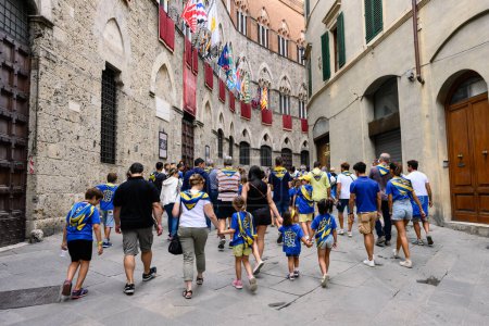 Téléchargez les photos : Sienne, Italie - 15 août 2022 : Des membres de la Tartuca ou Tortoise Contrada marchent sur la Via di Citta devant le Palazzo Chigi-Saracini - en image libre de droit