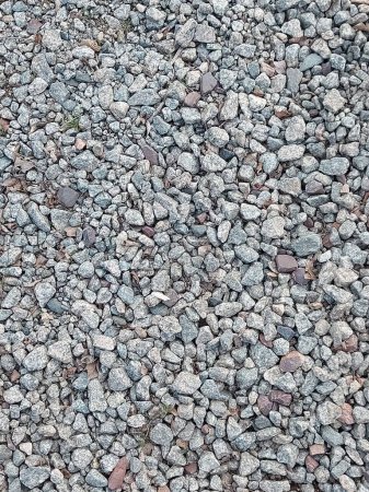 Granite gravel of macadam, rock gray crushed for construction on the ground. Scree texture background. Gravel is a loose aggregation of rock fragments. 