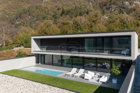 Außen moderne Villa mit Schwimmbad. Das Haus ist von Bergen umgeben. Niemand drinnen