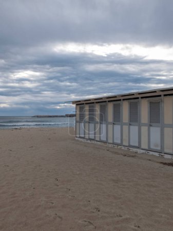Téléchargez les photos : Deserted Italian beach, no one around, we are towards evening with a cloudy sky. On the right you can see the closed cabins. - en image libre de droit