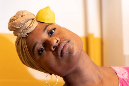Foto de Retrato de una mujer africana con un gran pendiente y un limón amarillo en su sien. - Imagen libre de derechos
