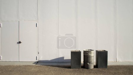 Foto de Un contenedor entre dos ceniceros gigantes con el fondo blanco de una pared en una zona industrial - Imagen libre de derechos