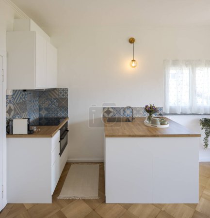 Téléchargez les photos : Vue de face d'une petite cuisine artistique avec un comptoir en bois et une petite fenêtre lumineuse. Personne à l'intérieur - en image libre de droit
