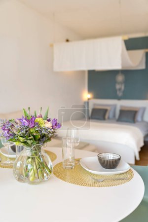 Photo for Detail of a place set for lunch, with a plate, cutlery and a glass. There is a bouquet of fresh flowers. Copy space - Royalty Free Image
