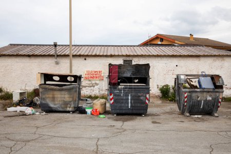 Téléchargez les photos : De grandes poubelles ouvertes avec des ordures éparpillées partout, c'est juste de la grossièreté. Zone dégradée de la ville - en image libre de droit