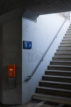Téléchargez les photos : Détail d'un escalier dans une gare avec la machine de validation des billets orange à côté. Personne à l'intérieur - en image libre de droit