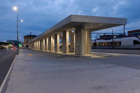Photo for Modern bus stop shelter with the train station behind it in Mendrisio. Modern infrastructure in Switzerland. Nobody inside. - Royalty Free Image