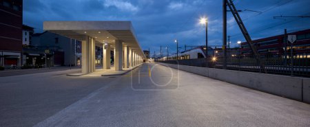 Téléchargez les photos : Abri d'arrêt de bus moderne avec la gare de Mendrisio à côté. Infrastructures modernes en Suisse. Vue de face, personne à l'intérieur. - en image libre de droit
