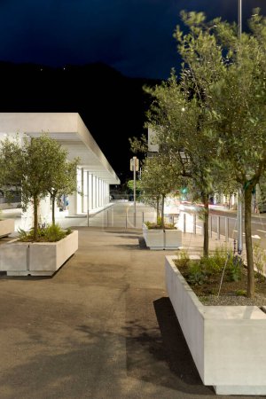 Téléchargez les photos : Abri d'arrêt de bus moderne à Mendrisio, au premier plan pots en béton avec des plantes. Infrastructures modernes en Suisse. Vue de face, personne à l'intérieur. - en image libre de droit