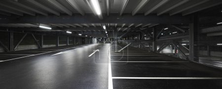 Photo for Modern underground garage with lamps illuminating the scene. Parking lines are drawn on the floor. No one inside - Royalty Free Image