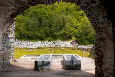 Foto de Bañeras termales con vistas al río y a la naturaleza suiza. Vista desde el interior de una cueva. Nadie adentro, vista frontal., - Imagen libre de derechos
