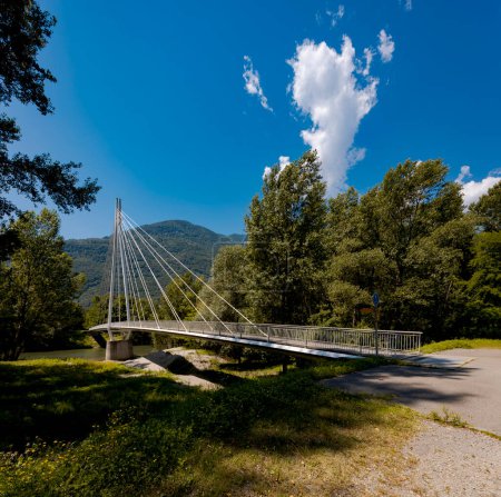 Foto de Moderno puente peatonal en medio de las montañas de la Suiza italiana, que le permite cruzar el río Ticino. Hermoso día de verano soleado. - Imagen libre de derechos