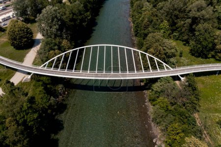 Photo for Aerial view of a modern arch shaped design pedestrian bridge over the Ticino river in Switzerland. Nobody inside - Royalty Free Image