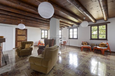 Foto de Interior de un gran salón y comedor con chimenea. Hay muebles viejos y anticuados. Una casa de vacaciones en las montañas - Imagen libre de derechos