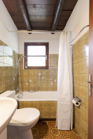 Photo for Interior. Old bathroom with brown tiles on the walls. you can see the bathtub the sink and the toilet. No one inside - Royalty Free Image