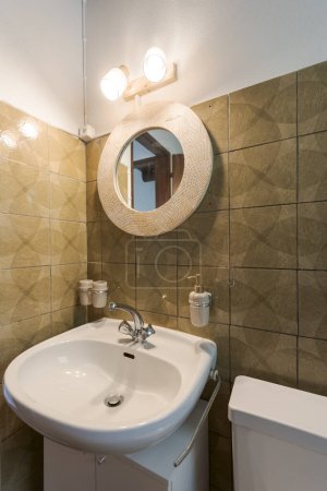 Photo for Detail of a washbasin a round mirror, lights on - Royalty Free Image