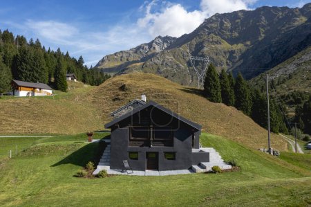 Téléchargez les photos : Un chalet de montagne suisse très insolite car il est noir et en bois. Entouré d'une belle prairie verte d'été. Le ciel est bleu et il ressemble à un endroit calme et très paisible. - en image libre de droit