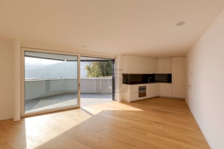 Foto de Dentro de un gran estudio nuevo con cocina y suelos de madera. La habitación tiene su propia terraza con un suelo de piedra. - Imagen libre de derechos