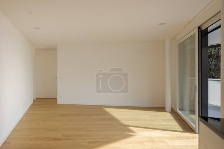 Téléchargez les photos : Chambre vide vue de face avec un mur blanc devant et une porte à gauche et une fenêtre à droite. - en image libre de droit