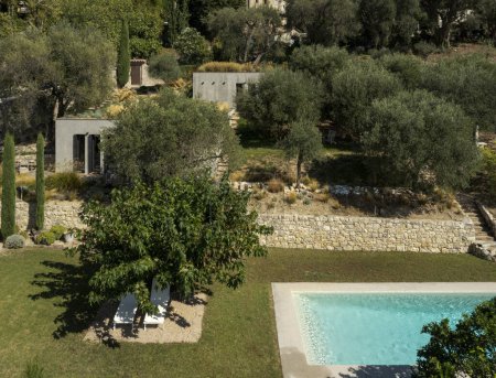 Foto de Vista aérea de una casa de campo moderna hecha de hormigón crudo en una parcela llena de olivos. Un hermoso día soleado rodeado de naturaleza. - Imagen libre de derechos