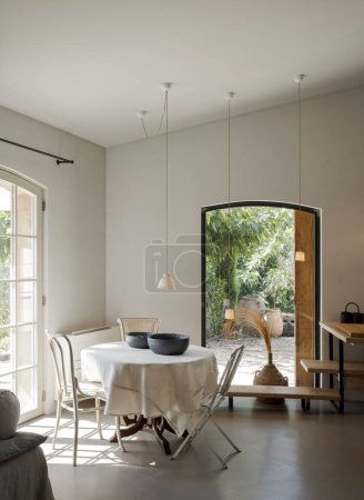 Téléchargez les photos : Vue de face du coin cuisine avec une table et des chaises à gauche, meubles à droite. L'intérieur est moderne et minimaliste. Il n'y a personne.. - en image libre de droit