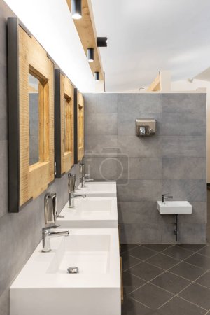 Téléchargez les photos : Salle de bain publique avec trois lavabos, miroirs et distributeurs de savon. Moderne et simple. Vue frontale - en image libre de droit