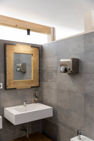 Téléchargez les photos : Détail d'un évier avec un miroir en osier et un sèche-mains. Personne à l'intérieur - en image libre de droit