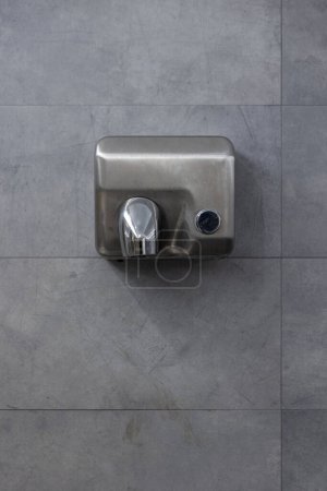 Téléchargez les photos : Détail d'un sèche-mains suspendu sur un mur de tuiles grises. Vue de face. Espace de copie - en image libre de droit
