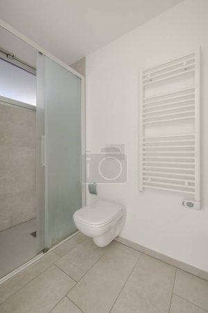 Téléchargez les photos : Petite salle de bain avec radiateur, WC et douche ouverte. Il y a aussi une petite fenêtre. Personne à l'intérieur - en image libre de droit
