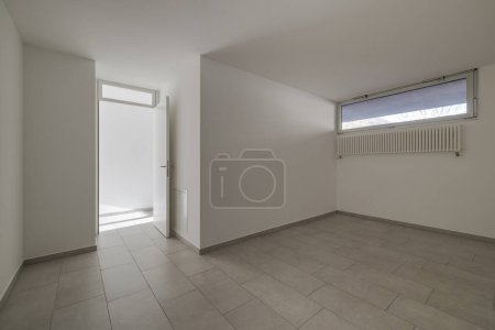 Photo for Room with white walls and a small window and an open door leading to the corridor. Nobody inside - Royalty Free Image