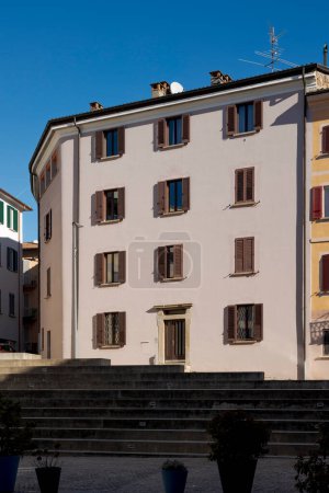 Antigua casa recientemente reformada en el centro de un pequeño pueblo en Ticino, con muchas ventanas y persianas, algunas abiertas, algunas cerradas. Nadie dentro.