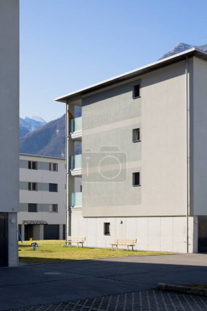 Photo for Detail of a residential complex with garden and games for children. There is blue sky and mountains behind, no one inside - Royalty Free Image