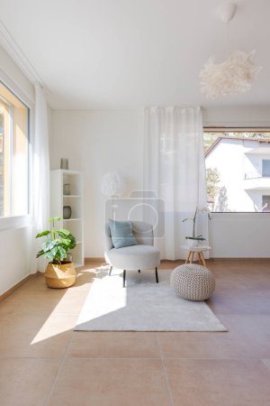 Photo for Detail of a living room corner with a small armchair with a coffee table and a pouf resting on the carpet. No one inside - Royalty Free Image