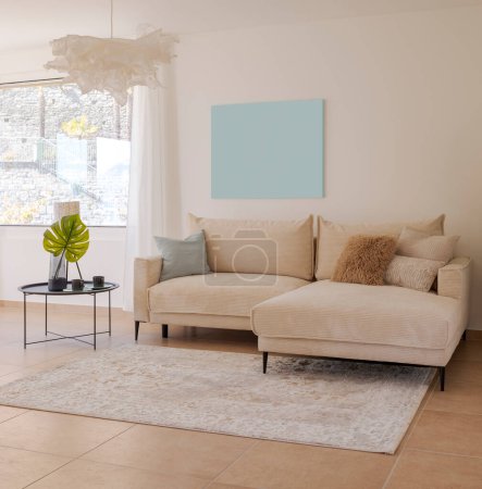Téléchargez les photos : Détail du salon avec un canapé en tissu léger avec des coussins et une petite table avec des plantes à côté. Au-dessus du canapé, il y a de l'espace pour une table. Personne à l'intérieur - en image libre de droit