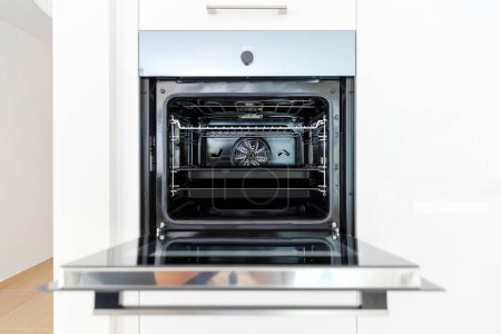 Foto de Detalle de un nuevo horno abierto con dos bandejas para hornear en el interior. Interior de una moderna cocina blanca. Nadie dentro. - Imagen libre de derechos