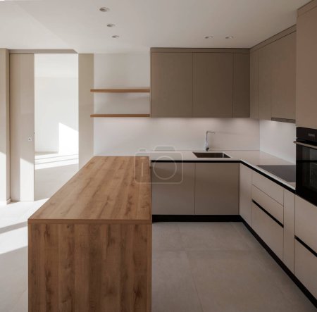 Foto de Interior de una nueva cocina moderna con encimera de madera. Todo es muy limpio y directo. un nuevo espacio para cocinar. - Imagen libre de derechos