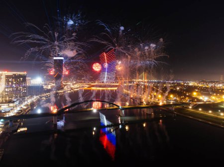 Drone flight above colorful fireworks on the black sky background over-water.