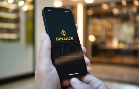 Photo for Alanya, Turkey - May 2, 2023: Man hand holding iPhone 14 with app cryptocurrency exchange Binance on the screen. iPhone was created and developed by the Apple inc - Royalty Free Image