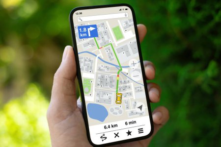 Téléchargez les photos : Téléphone portable homme avec application de navigation sur fond d'écran de rue verte - en image libre de droit
