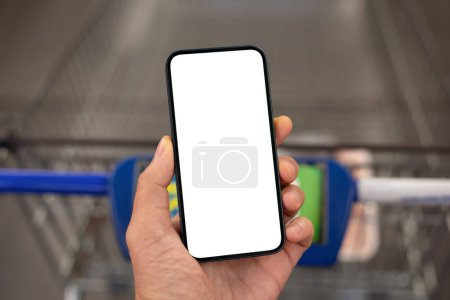 Foto de Teléfono de mano masculino con pantalla aislada sobre el carrito de compras en la tienda - Imagen libre de derechos