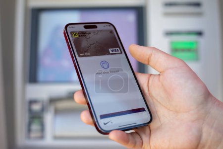 Téléchargez les photos : Alanya, Turquie - 12 mars 2024 : Homme tenant l'iPhone 15 Pro Max avec app Carte Apple Pay Visa Raiffeisenbank à l'écran. iPhone 15 a été créé et développé par Apple inc. - en image libre de droit