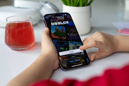 Photo for Alanya, Turkey - April 11, 2024: Children hands holding iPhone 15 Pro Max with multiplayer online game Roblox mobile in the screen IOS phone. Games Roblox was created by the Roblox Corporation. - Royalty Free Image