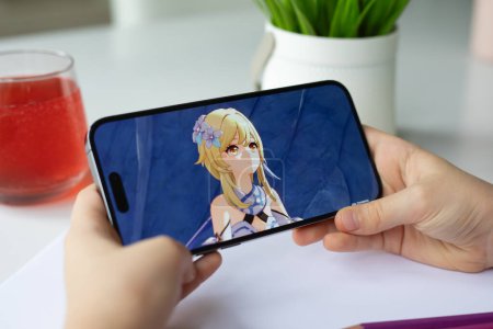 Photo for Alanya, Turkey - April 11, 2024: Children hands holding iPhone 15 Pro Max with game Genshin impact mobile in the screen IOS phone. Games Genshin impact was created by the miHoYo Limited. - Royalty Free Image