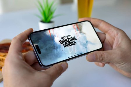 Téléchargez les photos : Alanya, Turquie - Mai 3, 2024 : Homme mains tenant téléphone Apple iPhone 15 Pro Max avec jeu Call of Duty Mobile à l'écran. Games Call of Duty a été créé par Activision Publishing, inc.. - en image libre de droit