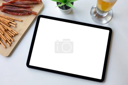 tableta de ordenador con pantalla de fondo aislado mesa blanca con cerveza y aperitivos en la cafetería ba