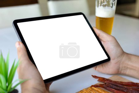 male hands hold computer tablet with isolated screen background white table with beer and snacks in cafe bar